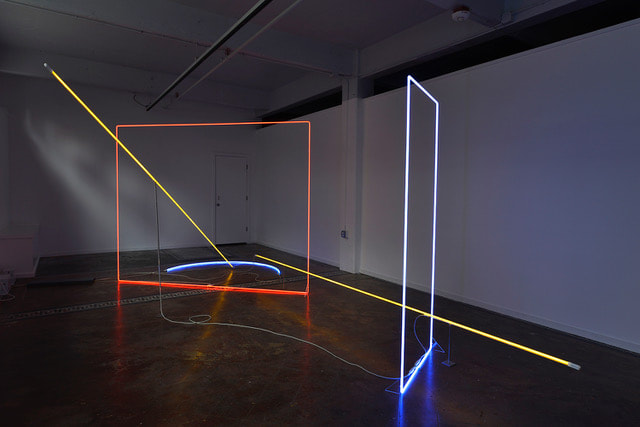 Neon Artwork, one large red square, one tall blue rectangle and two long yellow straight bars. 
